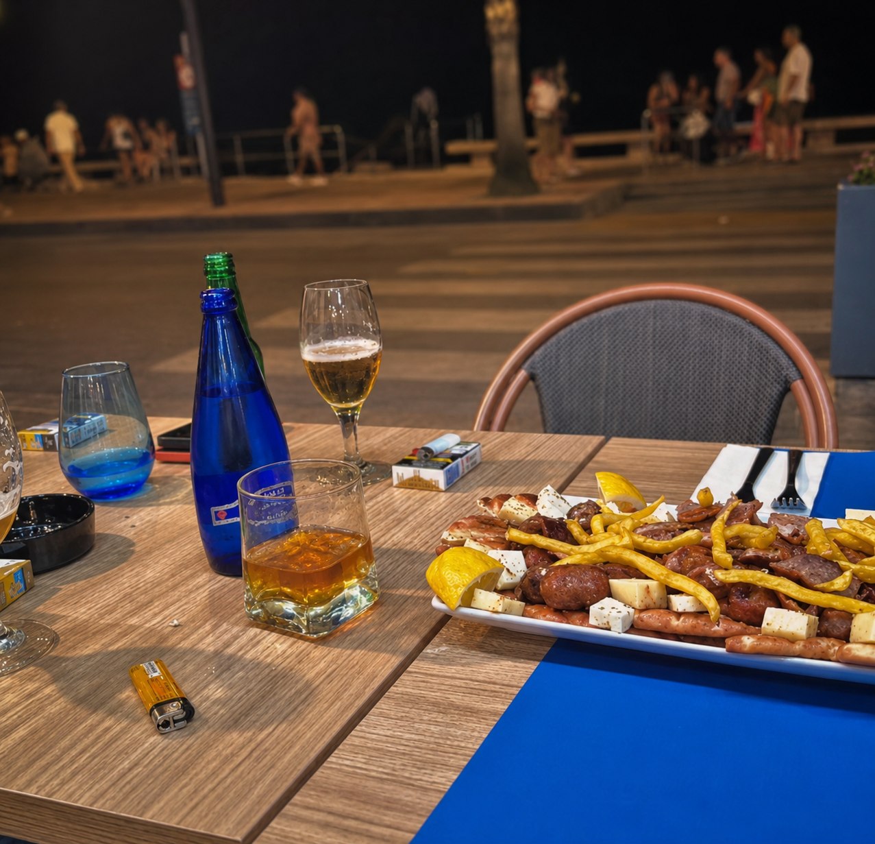 Greek meze platter with feta, sausages and drinks on the King Souvlaki terrace at night