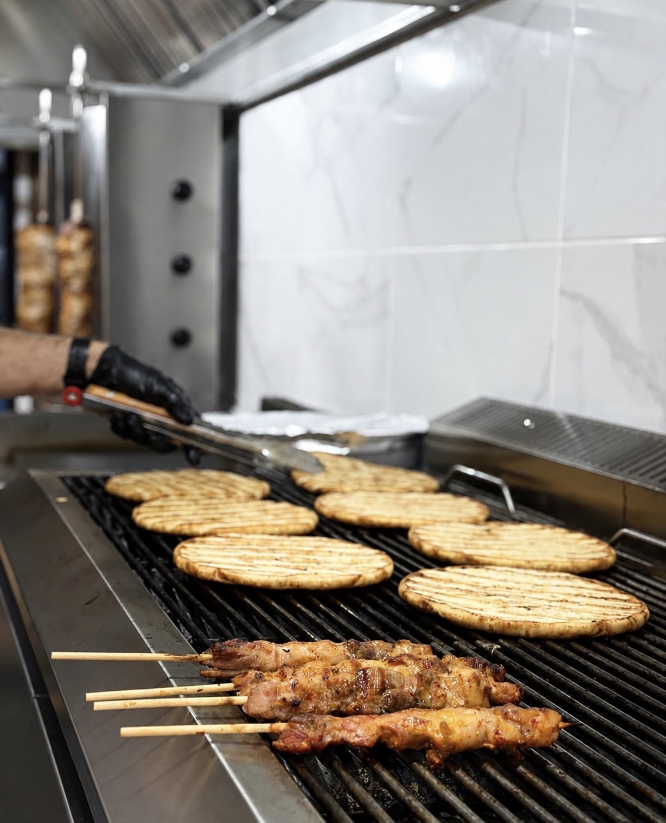 Fresh chicken souvlaki skewers and pita bread on the grill at King Souvlaki